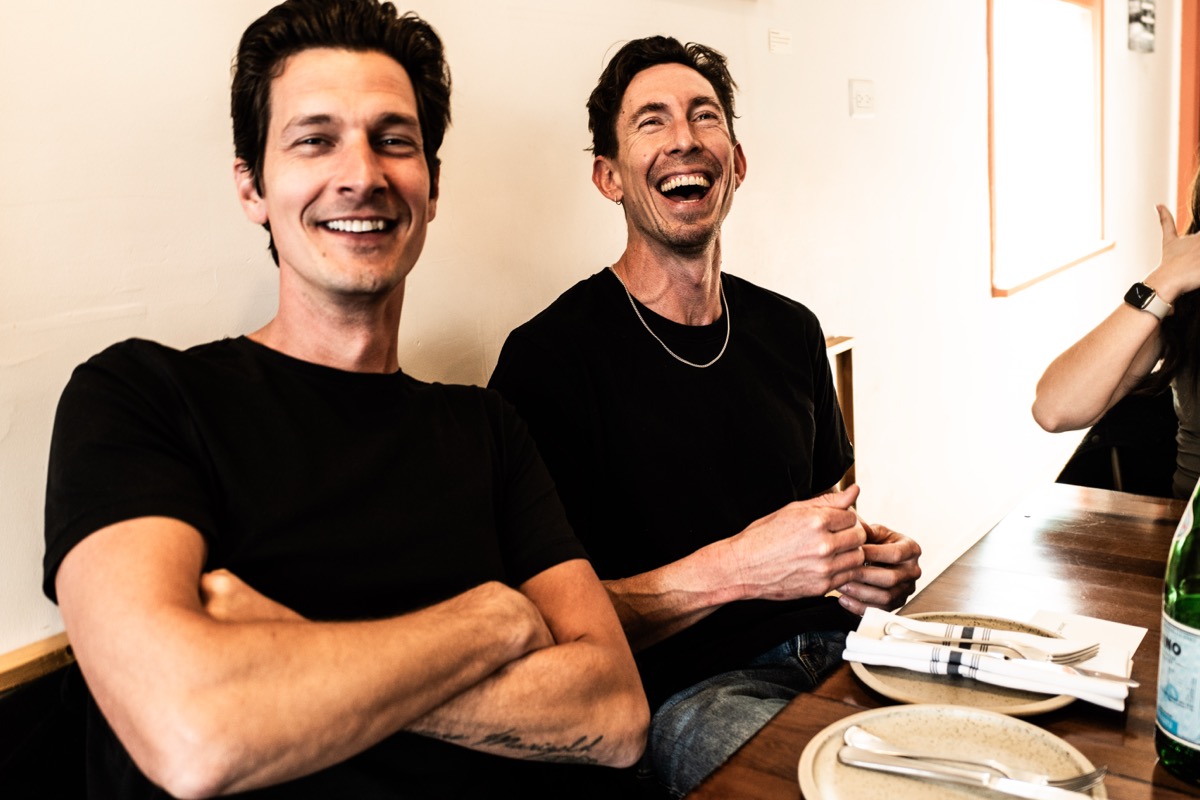 Two members in black t-shirts cracking up at the table