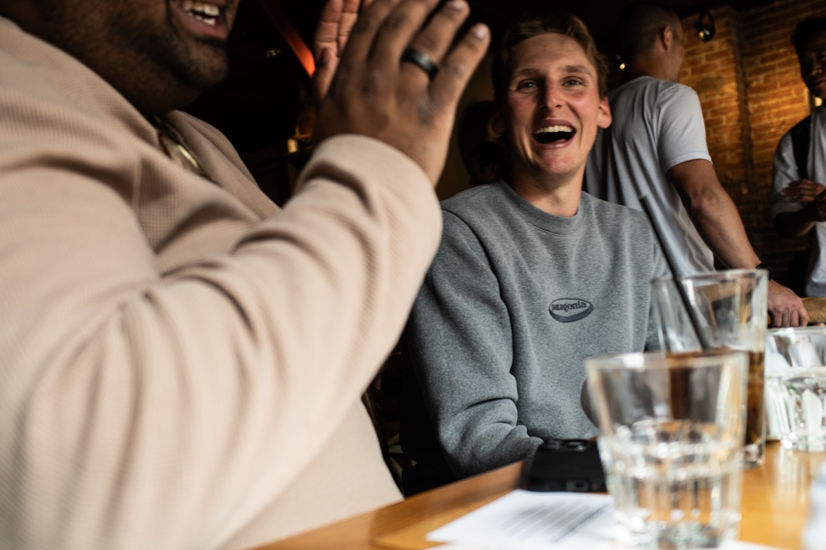 A high five going up over the table while a member laughs